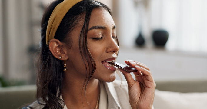 Home, relax and woman with chocolate bar, candy and eating with dessert, hungry or sugar. Person, apartment or girl on a sofa, smile or sweet treats with a snack, nutrition or diet plan with cacao