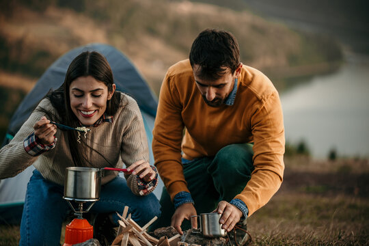 Lakeside camping with noodle cooking for a diverse couple using a stove - Powered by Adobe