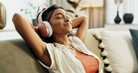 Woman, headphones and relax with music, sofa and peace with sound, smile or hearing in home living room. Girl, listening and audio streaming subscription on lounge couch, happy or radio show in house - obrazy, fototapety, plakaty