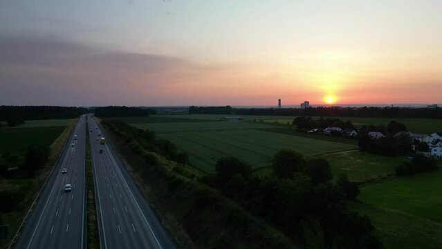 Bright orange sunlight in distance. Countryside and highway below. Aerial