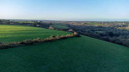 A thin hedge wraps around the top of a hill. Sunlight streaking across the top of the field. Taken...