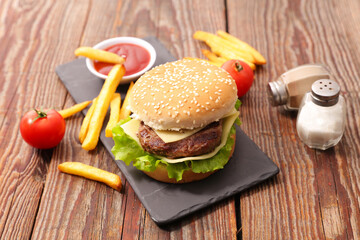 Tasty burger with beef and cheese, french fries and ketchup