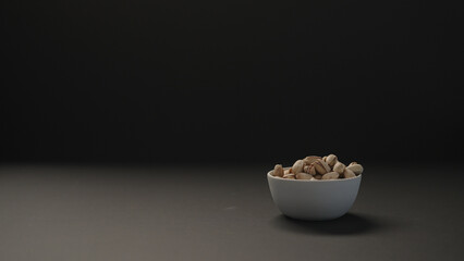 salted large pistachios in white bowl on black paper background
