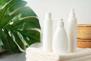Set of blank cosmetic bottles and towels on gray background