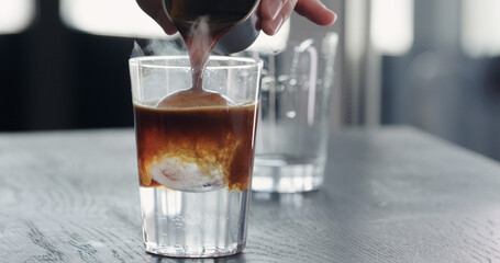 pour espresso into tonic with clear ice cube in tumbler glass on black oak table - obrazy, fototapety, plakaty