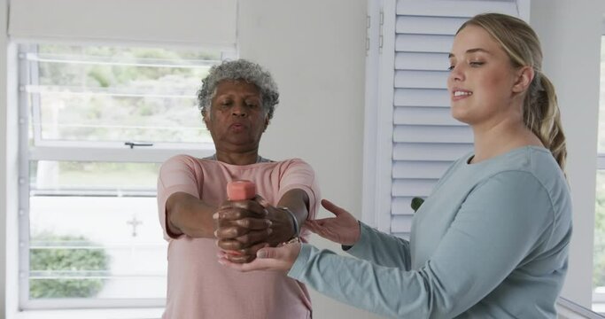 Caucasian female physiotherapist with senior woman exercising, copy space, slow motion
