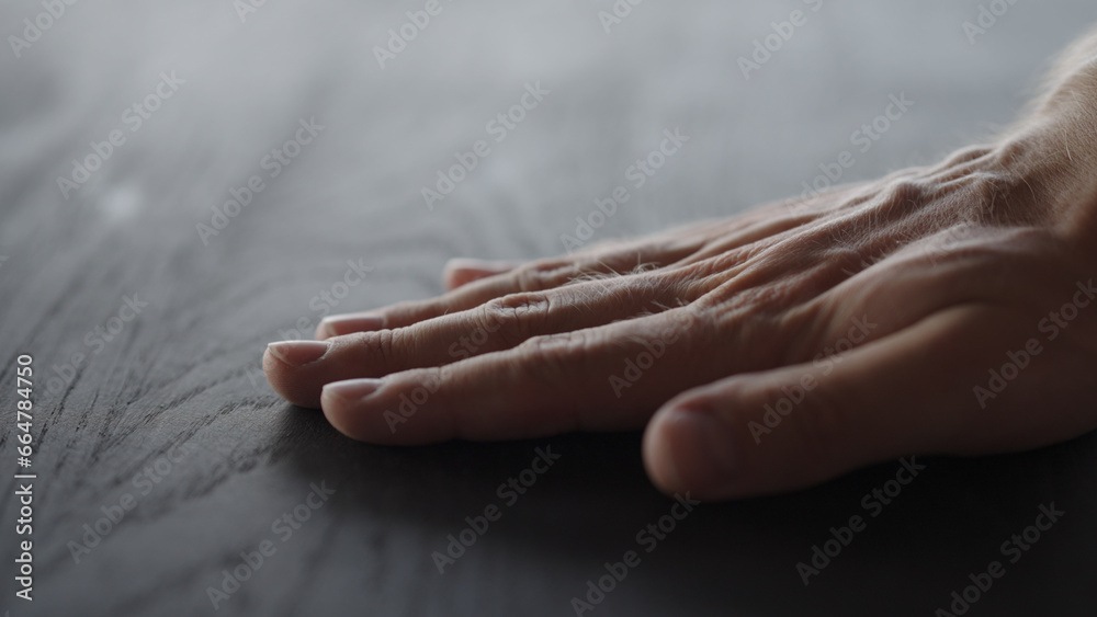 Wall mural man hand touches black oak table surface