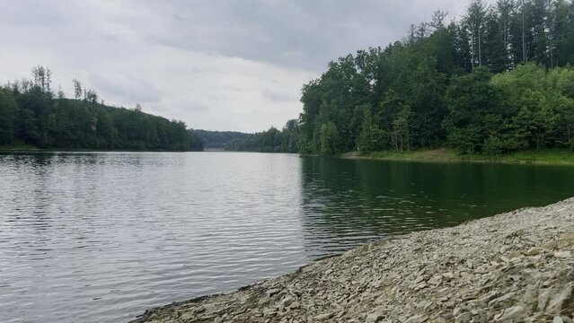 Bank of the aggertalsperre with a large lake and forest in the background