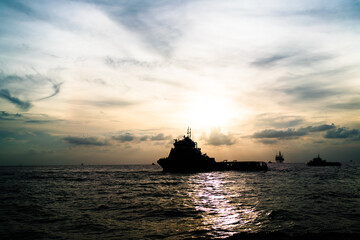 Fototapeta premium Transport ship of offshore gas and oil drilling platform in petroleum industry at sunrise morning.