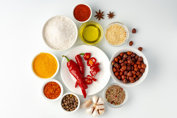 Bowls with spices and cooking ingredients on white background
