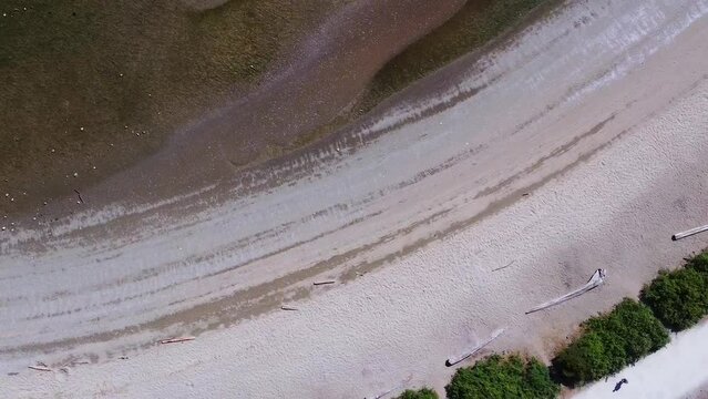 Aerial footage moving over a sandy beach towards the ocean 