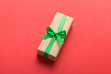 Wrapped christmas or other holiday handmade present in craft paper with colored ribbon. Present box, decoration of gift on table, top view with copy space