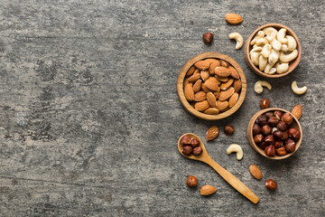 Assortment of nuts in wooden bowl on colored table. Cashew, hazelnuts, walnuts, almonds. Mix of nuts Top view with copy space