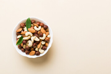Assortment of nuts in wooden bowl on colored table. Cashew, hazelnuts, walnuts, almonds. Mix of nuts Top view with copy space