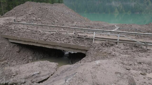 Heavy machinery toils in the muddy aftermath of a landslide, capturing the essence of nature's unpredictability and human resilience.