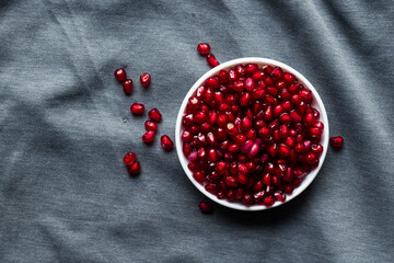 Ripe pomegranate seeds in a bowl on a black texture background