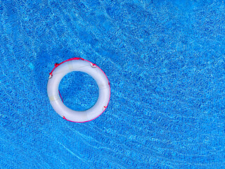 Top view of lifeboat floating in blue swimming pool, soft focus.