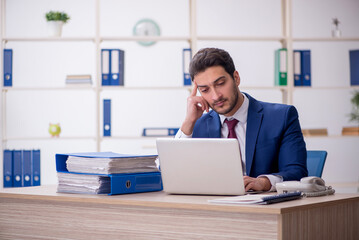 Naklejka premium Young male employee and too much work in the office
