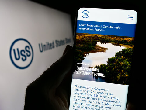 Stuttgart, Germany - 09-25-2023: Person holding cellphone with website of company United States Steel Corporation (US Steel) in front of logo. Focus on center of phone display.