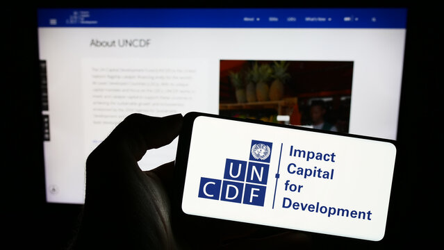 Stuttgart, Germany - 09-25-2023: Person holding mobile phone with logo of United Nations Capital Development Fund (UNCDF) in front of web page. Focus on phone display.