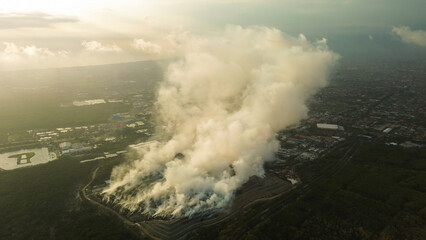 Aerial view of a long-range fire at a large landfill with garbage. A thick cloud of toxic smoke rises into the air. Problem with air pollution and waste recycling. The garbage is burning.