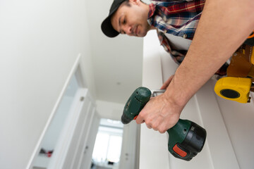 Male carpenter wood door installation working tightens lock.