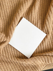 An empty white square mockup on a beige knitted background. Minimalism