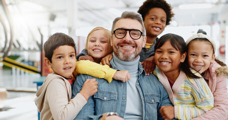 Education, portrait and group of children with teacher at school with happiness for development. Man, kids or face with smile in classroom for knowledge, support and teaching with confidence and joy