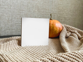 A cozy composition with an orange pumpkin, a beige sweater on a black table, and a place for text. copy space