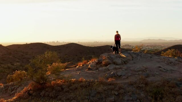 Aerial orbit around woman with her pet dog friend enjoying sunset in Arizona