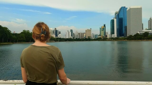 Parks and Recreation in Bangkok Thailand. 4K approaching shot of a woman enjoying her scenic walk through Bejakitti Park. Lake Ratchada Overlook.
