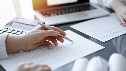 Woman accountant using a calculator and laptop computer while counting taxes for a client. Business...