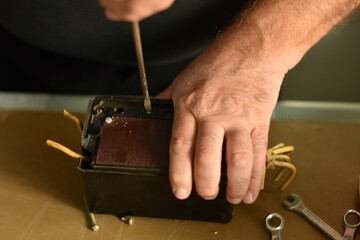 An electrician tightens the bolt on the back cover of an electric machine with a screwdriver.