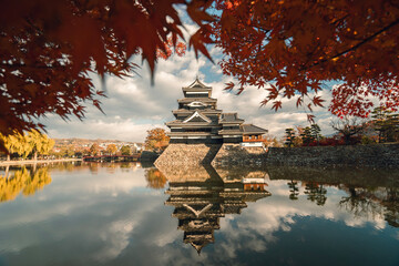 Matsumoto Castle in Autumn with Red Maple Leaf on Sunny Day, Crow Castle, Matsumoto, Nagano prefecture, Japan. Matsumoto Castle is one of Japan's premier historic castle.