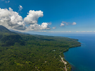 Camiguin Island with green mountain forest. Blue sea, blue sky and clouds, tropical landscape. Philippines.