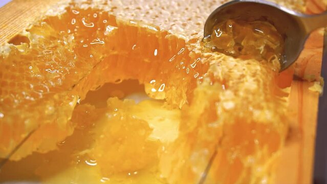 A Female Hand Picks Up with a Spoon Transparent, Liquid Honey from a Glass Jar. Yellow thick flow bee honey pouring, falling smoothly stream in the container. Healing, organic beekeeping product. 4K.