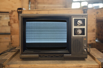 An old TV with noise on the screen sits on a box.