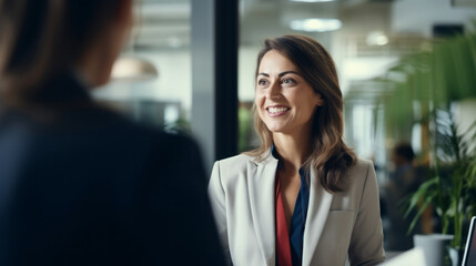 Businesswoman is talking to a female colleague, smiling, positive mood, in the office
