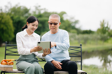 Elderly asian senior man on wheelchair with Asian careful caregiver. Nursing home hospital garden concept..