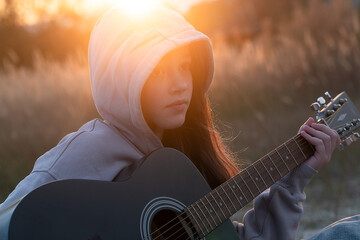 A young girl plays the guitar. Autumn beach and girl with guitar