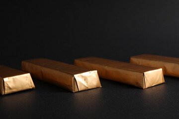 Chocolates in golden foil on black background, close up