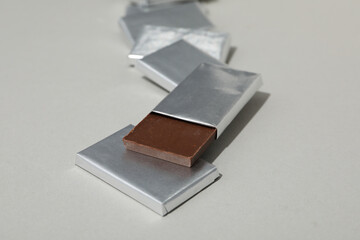 Chocolates in silver foil on gray background, close up