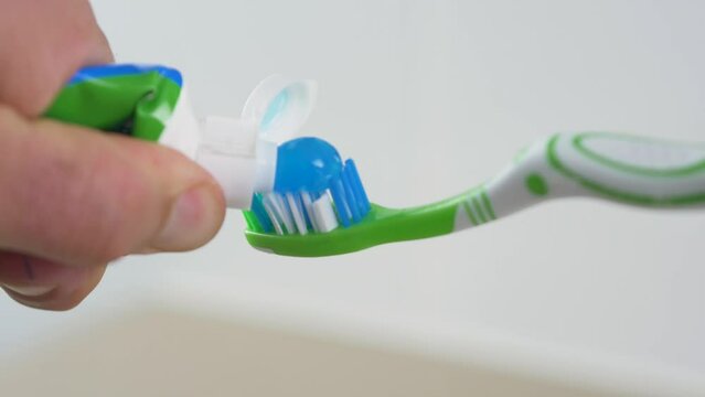 Close-up slow motion shot of toothpaste squeeze onto toothbrush dental gel cleaning personal hygiene health oral bathroom 4K