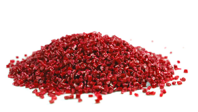 Secondary granule made of polypropylene, red Plastic pellets crumbles to the table. Plastic raw materials in granules for industry. Polymer resin. Raw plastic recycling concept