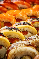 Close-up of various sushi rolls with salmon, shrimp, eel on a black slate board on a black background