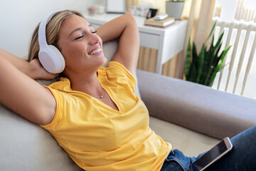Shot of an attractive young woman wearing headphones while relaxing on the sofa at home
