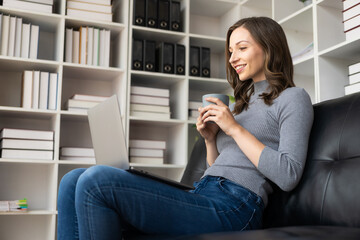 Beautiful young woman sitting on sofa looking at laptop screen Millennial students who are motivated to study remotely from home I am a female freelancer who works online.