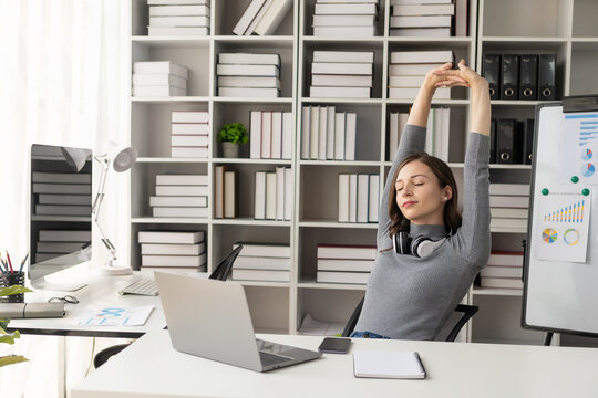 Happy young woman in her work at the office. Relaxing. Stretching her hands. Satisfied relaxed businesswoman sitting in a chair with hands in head enjoying her new job at the office.