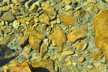 pebbles on a turquoise green lake in the French Pyrenees