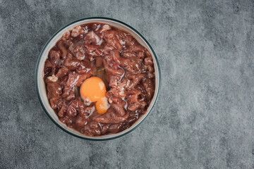 Seasoned marinated pork with yolk egg in a bowl, camping menu. Top view